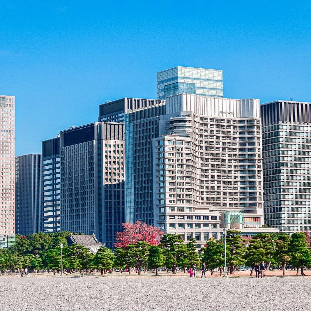a group of people walking on a beach in front of tall buildings
